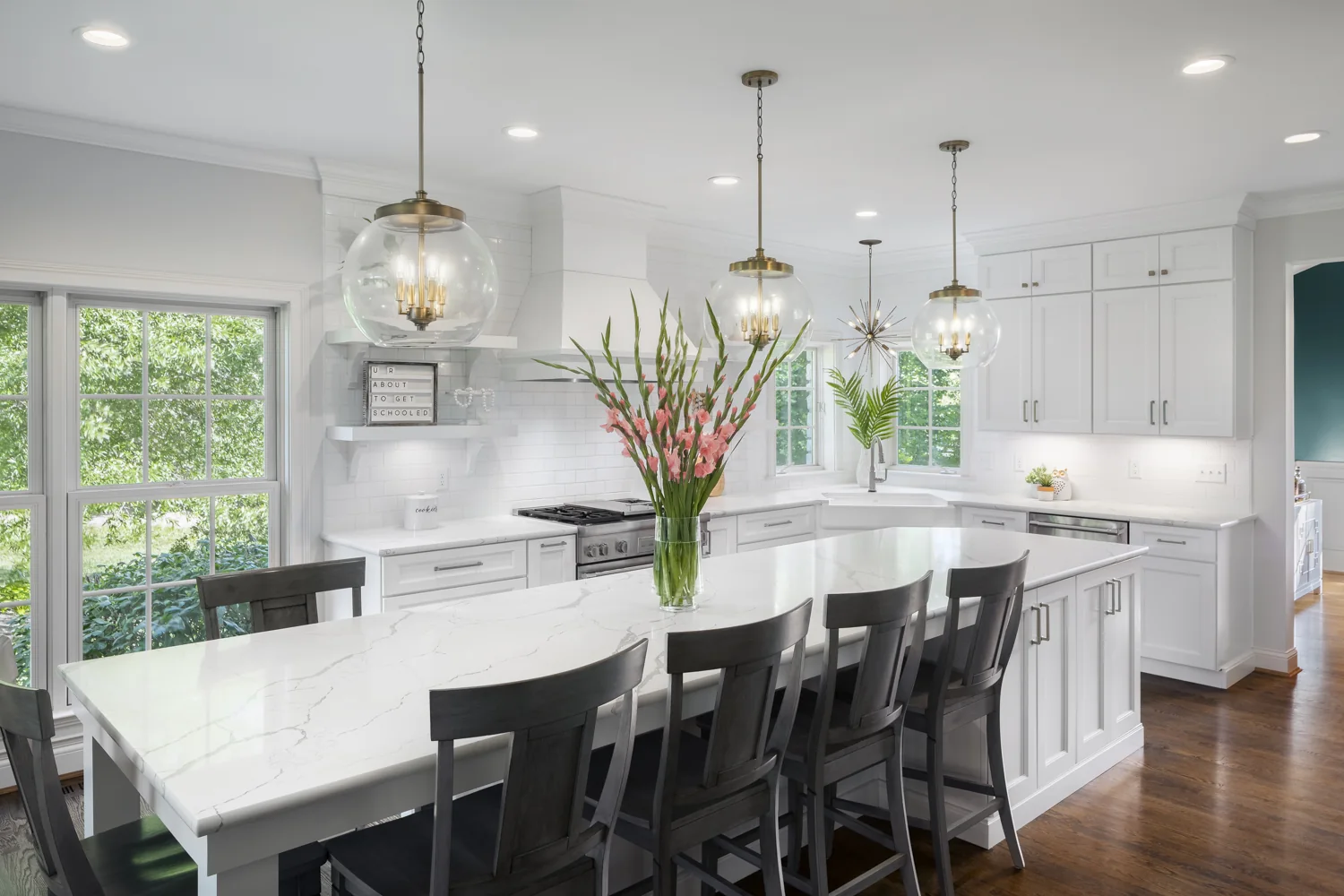 Bright kitchen designed with a large island and brass pendants