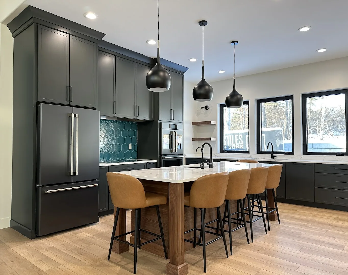 Dark kitchen with a long island and considered pendant lighting
